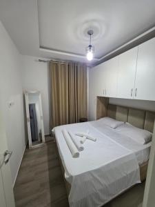 a bedroom with a large white bed with white cabinets at Solei Sea Apartment in Shëngjin