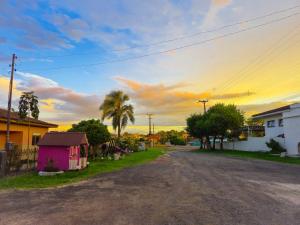 an empty street with a pink house and palm trees at Hotel El-Shaday in Vila Nova do Sul