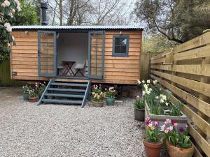 a tiny house with flowers in front of a fence at Shepherds Hut in Penzance in Newlyn +3 photos