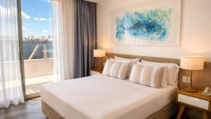 a bedroom with a white bed and a large window at Pinamar Beach Resort in Pinamar +58 photos