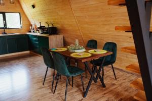 a dining room with a table and green chairs at A-Forest Retreat - David's A-frame in Ocna-Mureşului