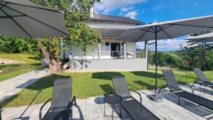 a patio with chairs and umbrellas in front of a house at Villa Sunset in Banja Luka