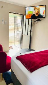 a bedroom with a bed with a tv on the wall at Umthombo guest house in Mbabane