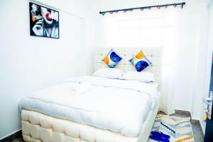 a bedroom with a white bed with pillows at AJHOMESKisumu in Kisumu