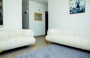 a living room with two white couches and a rug at AJHOMESKisumu in Kisumu