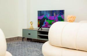 a living room with a white couch and a tv at AJHOMESKisumu in Kisumu