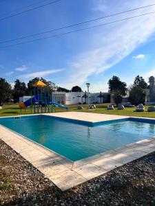 a swimming pool with a playground in a park at Hotel De Campo Firmat in Firmat