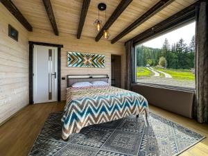 a bedroom with a bed and a large window at Будиночки Ґалєрія in Vaydry