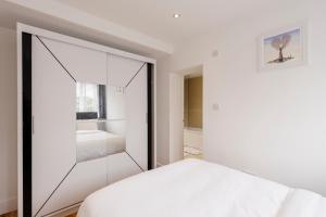 a bedroom with white walls and a large mirror at Sunnymede Court in Billericay