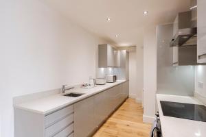 a white kitchen with white cabinets and a wooden floor at Sunnymede Court in Billericay +24 photos