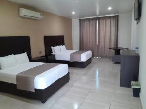 a hotel room with two beds and a desk at Hotel Visión in Tuxpan de Rodríguez Cano