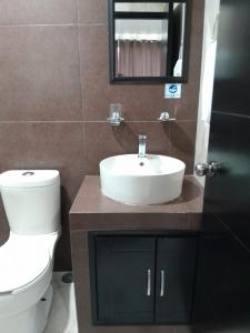 a bathroom with a sink and a toilet and a mirror at Hotel Visión in Tuxpan de Rodríguez Cano