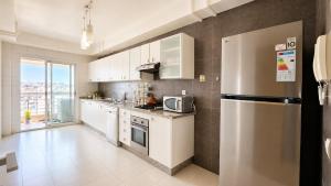 a kitchen with white cabinets and a stainless steel refrigerator at Central luxury apart Mohammedia in Mohammedia