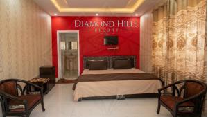 a bedroom with a large bed with a red wall at Diamond Hills Resort in Battakundi