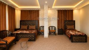 a hotel room with two beds and chairs at Diamond Hills Resort in Battakundi