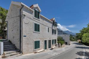 a stone house with green shutters on a street at Holiday Home Pelegrin in Brela