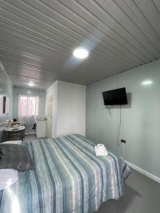 a bedroom with a bed and a tv on the wall at Hospedaje Oasis Modulares in Calama
