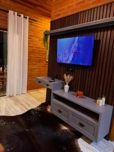 a living room with a flat screen tv on a wall at Vila do Sossego in São Bento do Sapucaí