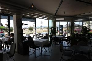 a dining room with tables and chairs and windows at Olivia Hotel in Durrës