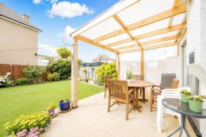a patio with a wooden pergola and a table and chairs at Ashwood Stays in Surbiton