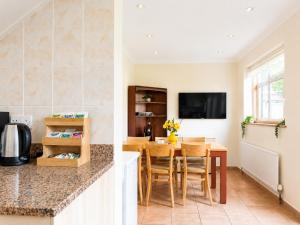 a kitchen and dining room with a table and a tv at Ashwood Stays in Surbiton