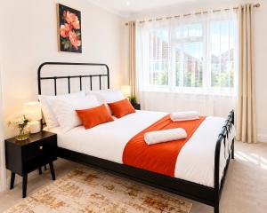 a bedroom with a large bed with orange and white pillows at Ashwood Stays in Surbiton