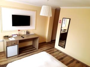 a hotel room with a desk and a television on the wall at Hotel Mic in Bucharest