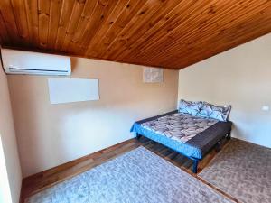 a small room with a bed and a wooden ceiling at Guest House Dacha in Karolino-Buhaz