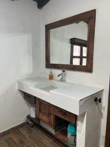 a bathroom with a white sink and a mirror at Hermosa cabaña de lujo MADERA in Tochimpa +17 photos