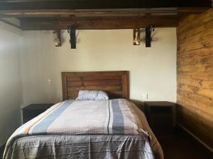 a bed in a bedroom with a wooden wall at Hermosa cabaña de lujo MADERA in Tochimpa