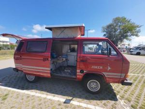 a red van parked in a parking lot with its door open at Retro Kamper Jastarnia in Jastarnia