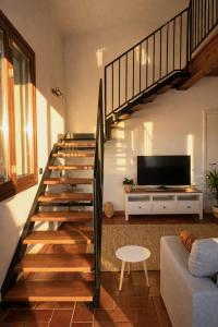 a living room with a staircase and a tv at Dolce Collina, Sunset Terrace & Vineyard Views in Dozza