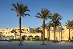 a group of palm trees in front of a building at TH Marina di Pisticci - Ti Blu Village in Marina di Pisticci