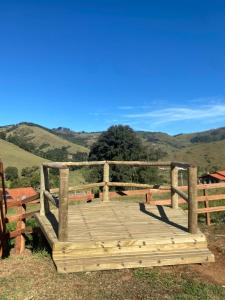 a wooden bridge with a fence and mountains in the background at Chalé Recanto da Paciência in Camanducaia