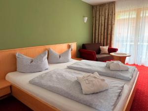 a hotel room with two beds and a chair at Residenz Dunza Hotel Garni in Bürserberg