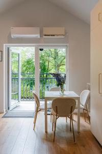 a dining room with a table and chairs and a balcony at NEMIRSETA FOREST Apartments in Palanga