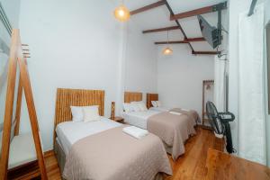 two beds in a room with white walls and wooden floors at Muyuterra in Moyobamba