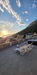two white lounge chairs on a roof with the sunset at Apartmani Šantić in Baška Voda