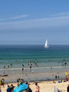 a crowd of people on a beach with a sailboat at Uno By The Sea - Boutique Hotel in St Ives