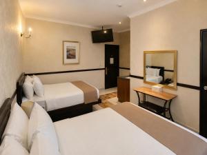 a hotel room with two beds and a mirror at Hotel Palacio Maya in Mérida
