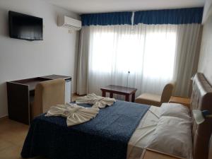 Schlafzimmer mit einem Bett, einem Schreibtisch und einem TV in der Unterkunft Hotel Gladiador in San Bernardo