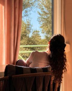 a woman sitting in a chair looking out a window at Olivet Hotel in Vlorë +34 photos