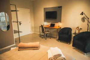 a living room with a desk and chairs and a television at Rio Branco 688 - Hospedagem Premium in Santa Maria