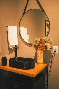 a bathroom sink with a mirror and a vase with flowers at Rio Branco 688 - Hospedagem Premium in Santa Maria +22 photos