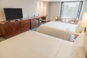 a hotel room with two beds and a flat screen tv at GHL Hotel Capital in Bogotá