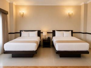 two beds in a hotel room with two lamps at Hotel Palacio Maya in Mérida