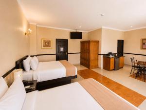 a hotel room with two beds and a television at Hotel Palacio Maya in Mérida