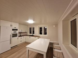 a kitchen with white cabinets and a white table at Unique Villa by a beautiful lake in Omberg