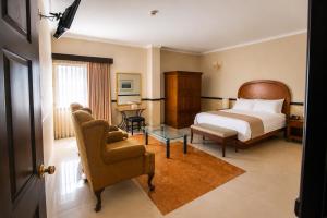 a hotel room with a bed and a chair at Hotel Palacio Maya in Mérida