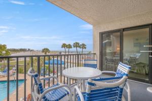 a balcony with a table and chairs and a pool at Caprice Resort by Travel Resort Services in St. Pete Beach